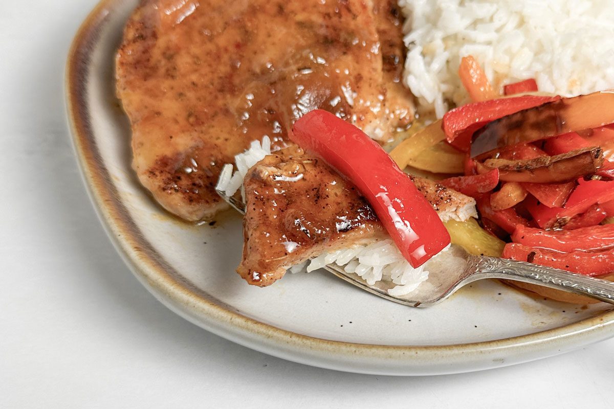 Taste of Home Jamaican Jerk Pork Chops on a plate with rice and peppers