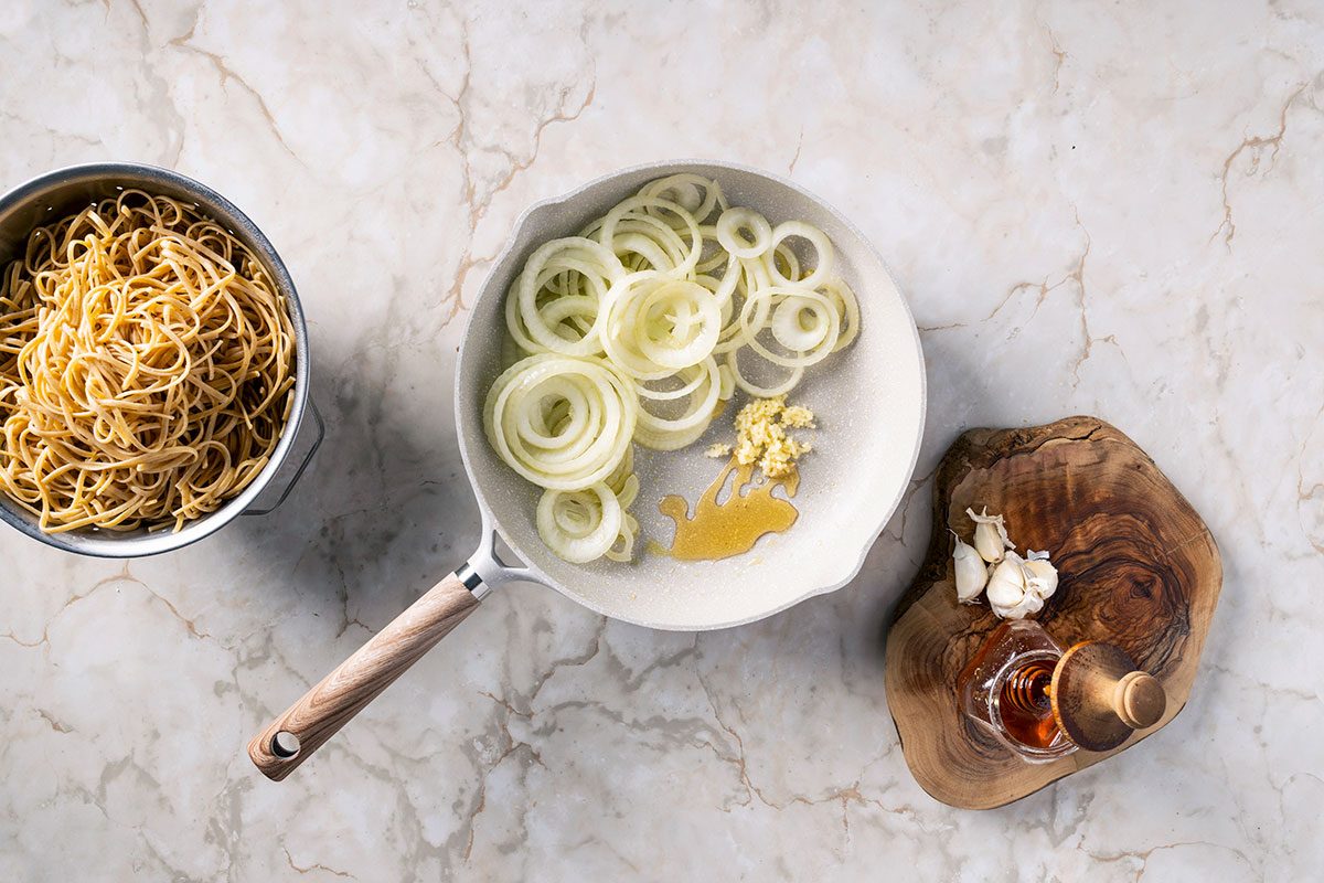 cooked linguine I na bowl and caramelized onions in skillet