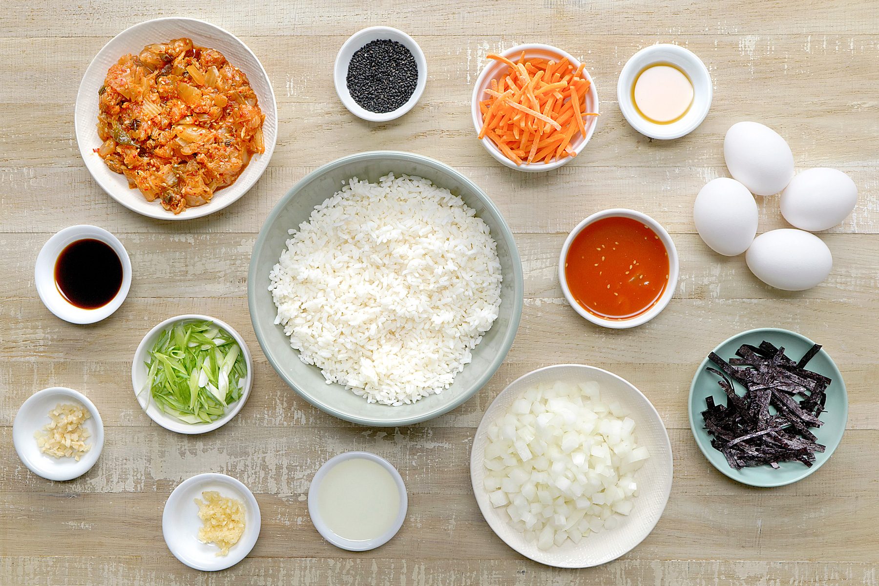 overhead shot of kimchi fried rice ingredients placed over wooden background;