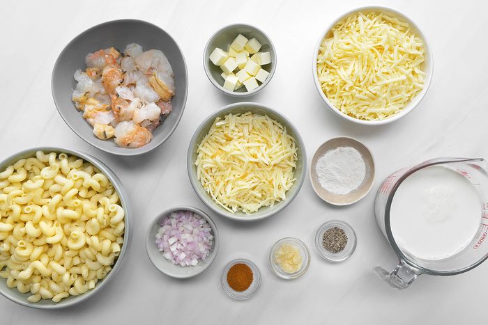 Butter, garlic, cheese, flour, seasonings, pasta and lobster tail meat in bowls.