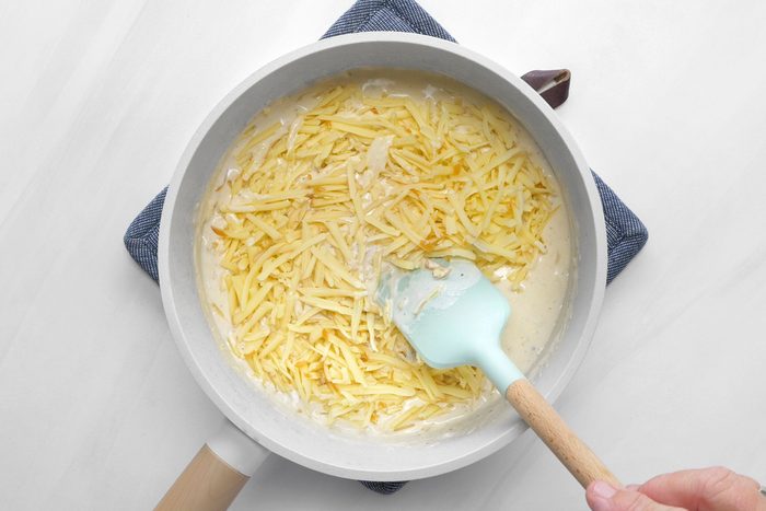 Cheese being added to the flour, butter and milk mixture.