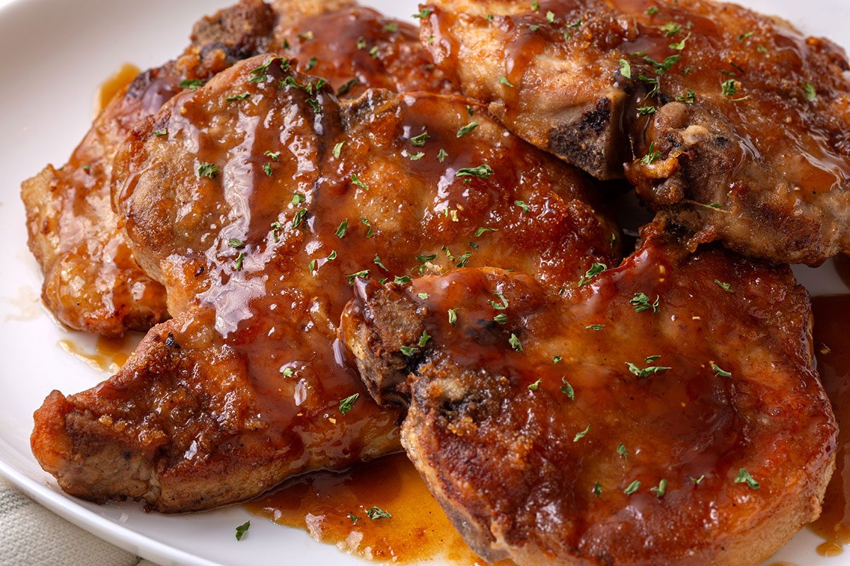 Close up of Maple-Glazed Pork Chops on a serving platter sprinkled with parsley for Taste of Home