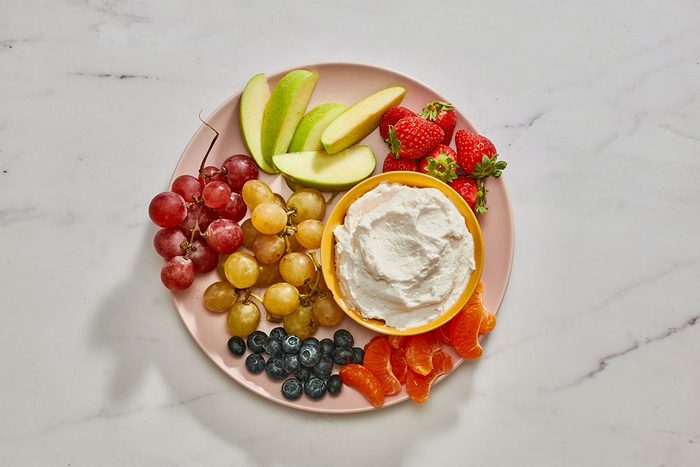 Marshmallow fruit dip in a bowl on a platter served with fresh fruits