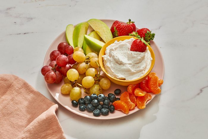Marshmallow fruit dip in a bowl on a platter served with fresh fruits
