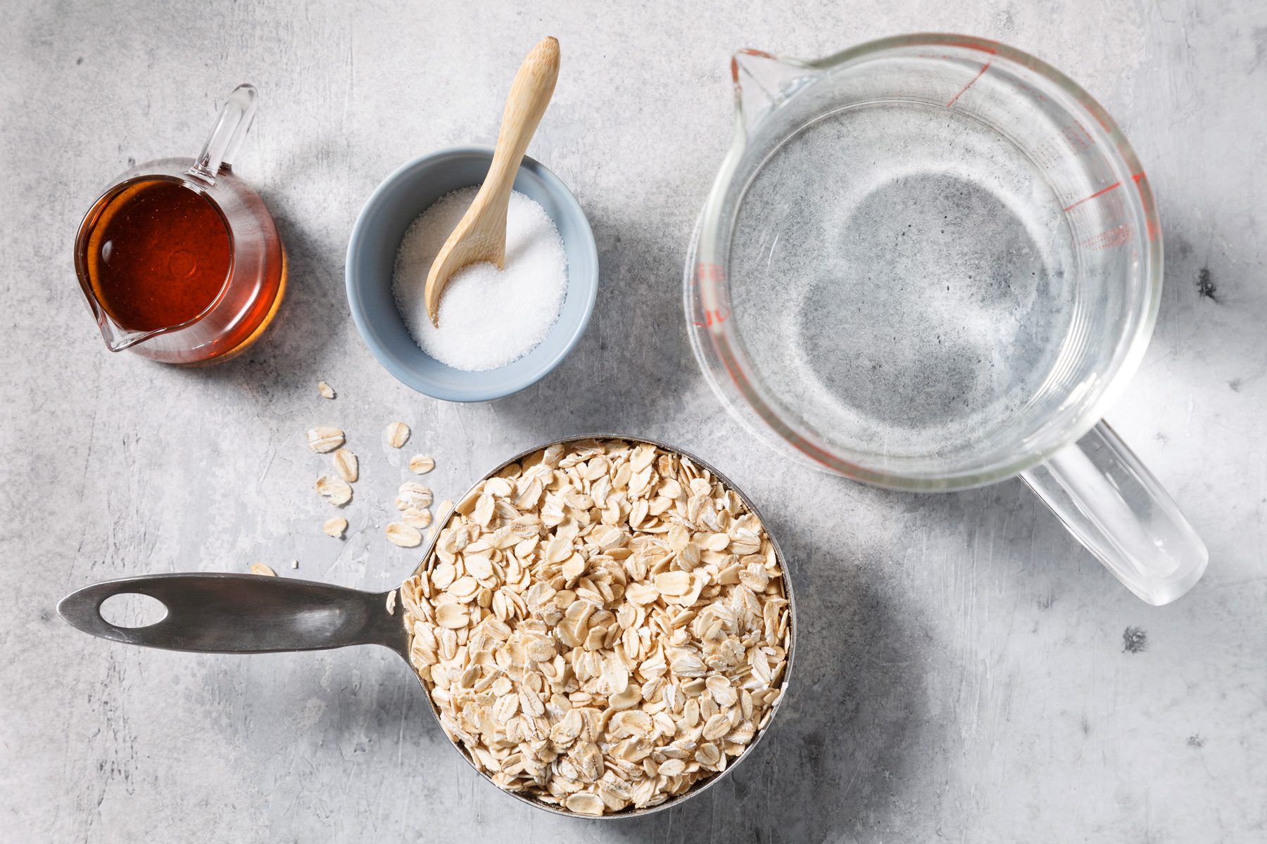 A bowl of oats with water, maple syrup, and salt arranged on a table, ready for preparation.