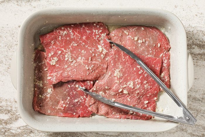 Beef marinating in a shallow dish for palomilla steak