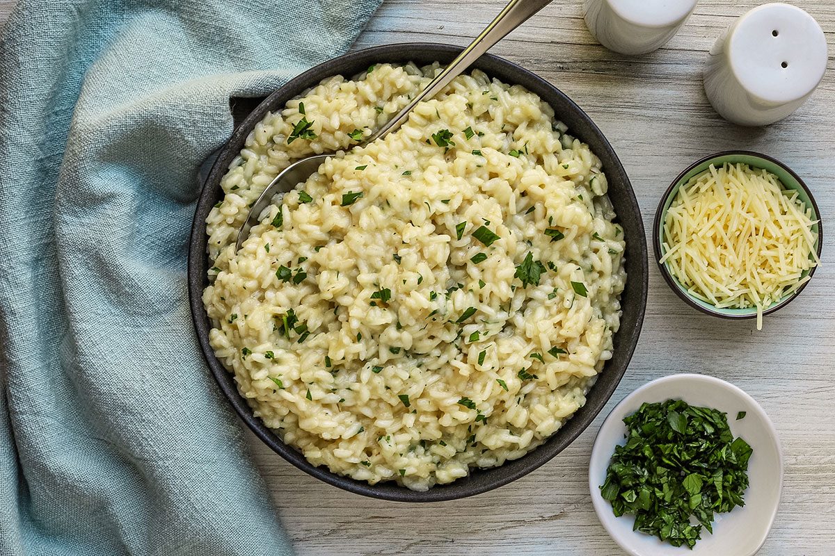 A serving of Parmesan risotto with extra parsley and shredded Parmesan cheese.
