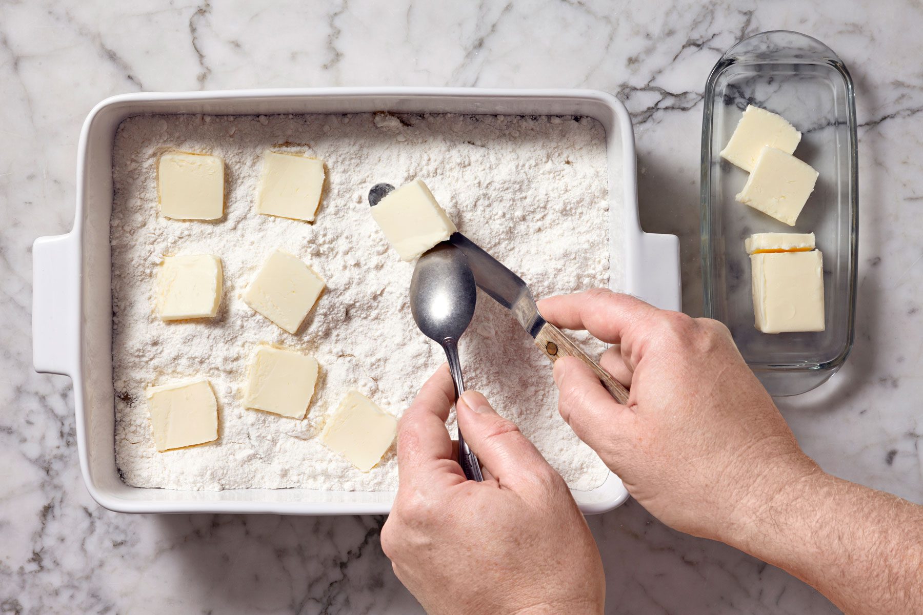 sliced butter being placed over cake mix in an even layer