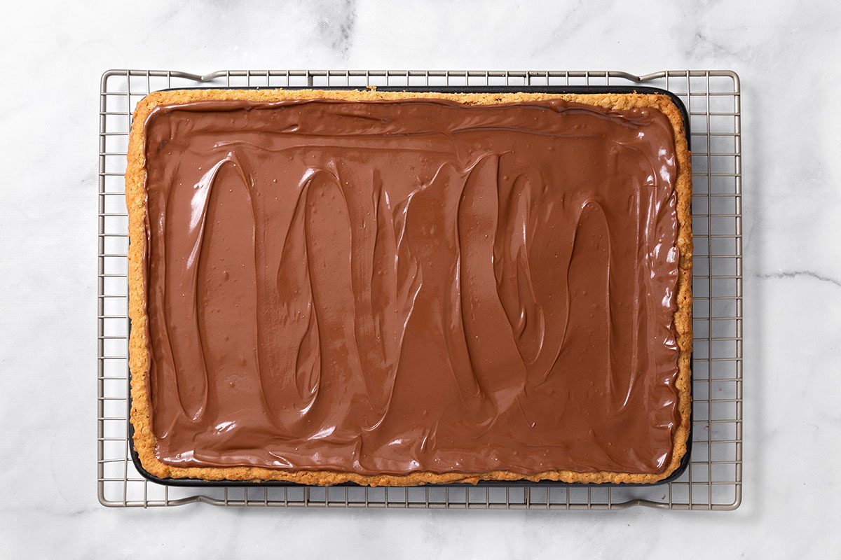 Melted chocolate and butterscotch chips, and peanut butter mixtured poured over baked cookie bars for step three of Peanut Butter Cookie Bars for Taste of Home
