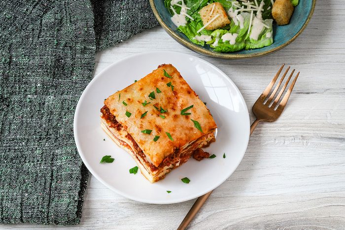 Overhead photo of pizza lasagna and Caesar salad.