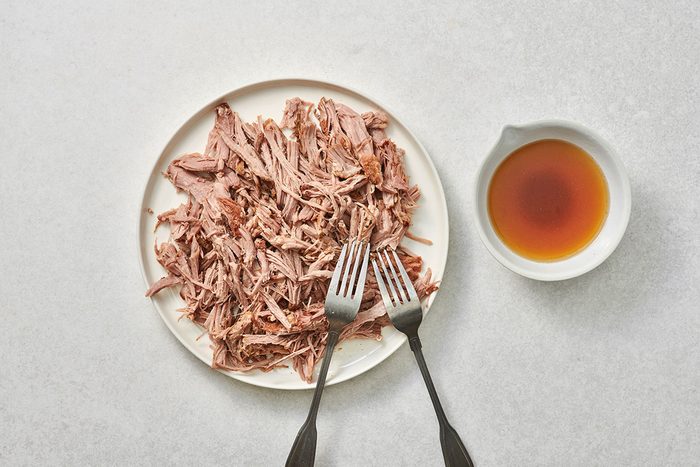 Shredded pork on a plate with reserved juices