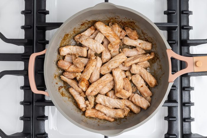 Pork loin being cooked in skillet.