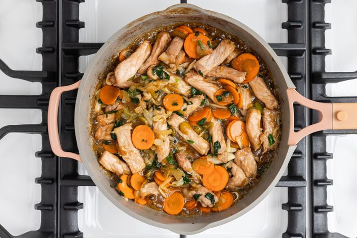 Pork loin and vegetables combined with sauce in skillet.