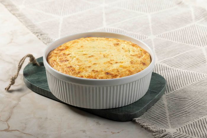 baked puffed and golden Potato Souffle in dish on marble at 3/4 view