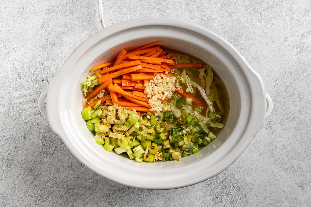 combining the ingredients, except the potstickers and crispy chow mein noodles, to the slow cooker.