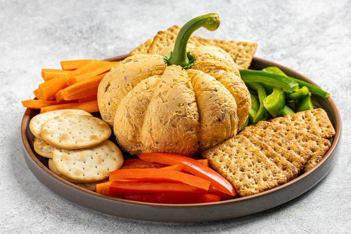 Taste of Home Pumpkin Cheese Ball photo of the green pepper stem added to the top of the unwrapped cheese ball resembling a pumpkin.