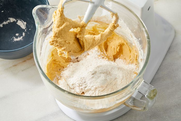 Shot of a third of the pre whisked dry ingredients going into the finished pumpkin mixture