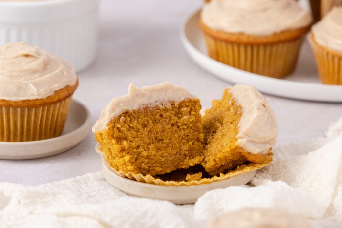 Pumpkin cupcake open to show inside with cupcake stand in the background.
