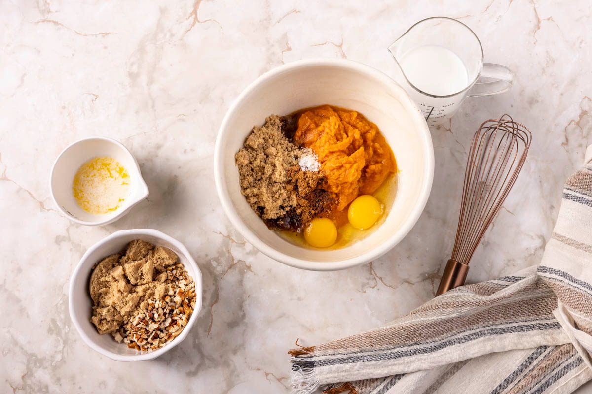 Pumpkin Custard in processes in a mixing bowl next to a whisk