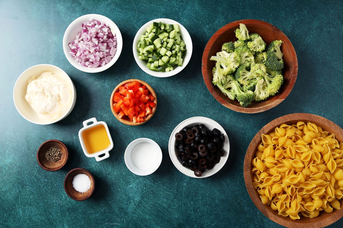 Ingredients for Taste of Home's Creamy Pasta Salad laid out in small bowls on green surface.