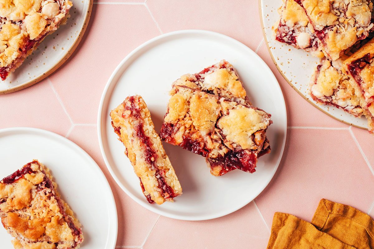 Multiple raspberry bars with coconut on small white plates, recipe by Taste of Home