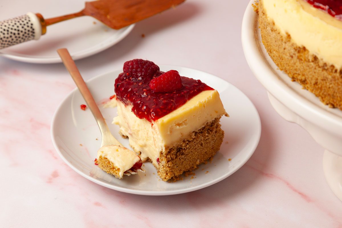 One slice of Taste of Home Raspberry Cheesecake, light pink surface, white and black pie server, full yield peaking in