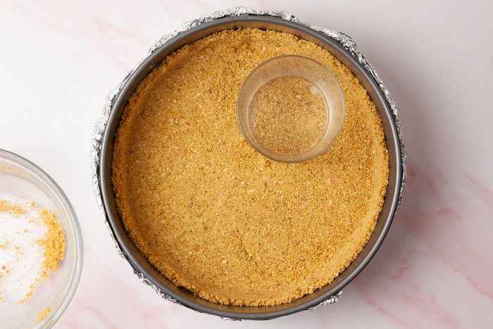 Step 1 of Taste of Home Raspberry Cheesecake is to combine the graham cracker crumbs, sugar and melted butter. Press the mixture firmly into the bottom of the prepared pan, pushing it about one inch up the sides. Place the pan on a baking sheet. Bake for 8 to 10 minutes until lightly browned, then cool completely.