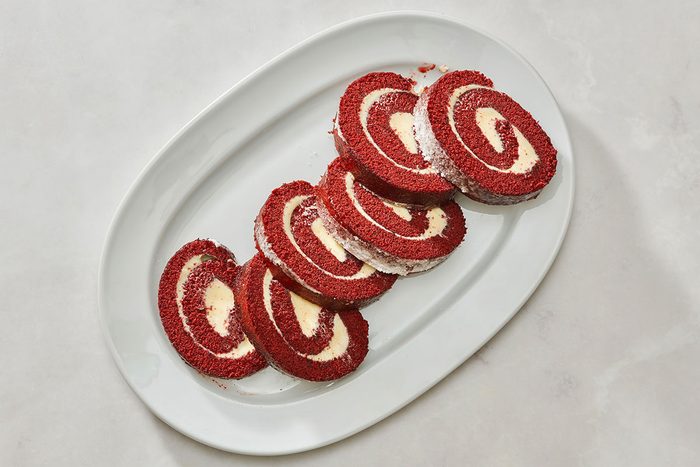 Red velvet cake roll served on a platter with a slice removed