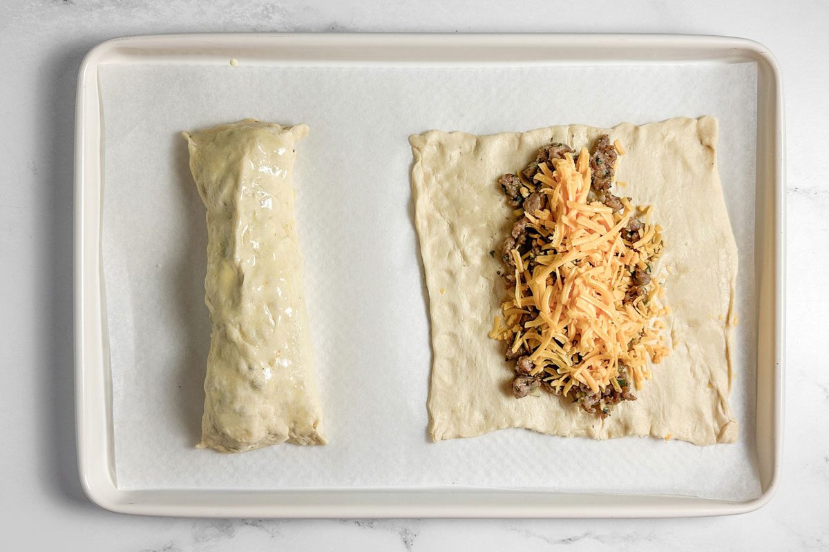 Rolled and unrolled Taste of Home Sausage Crescent Rolls on a white baking sheet
