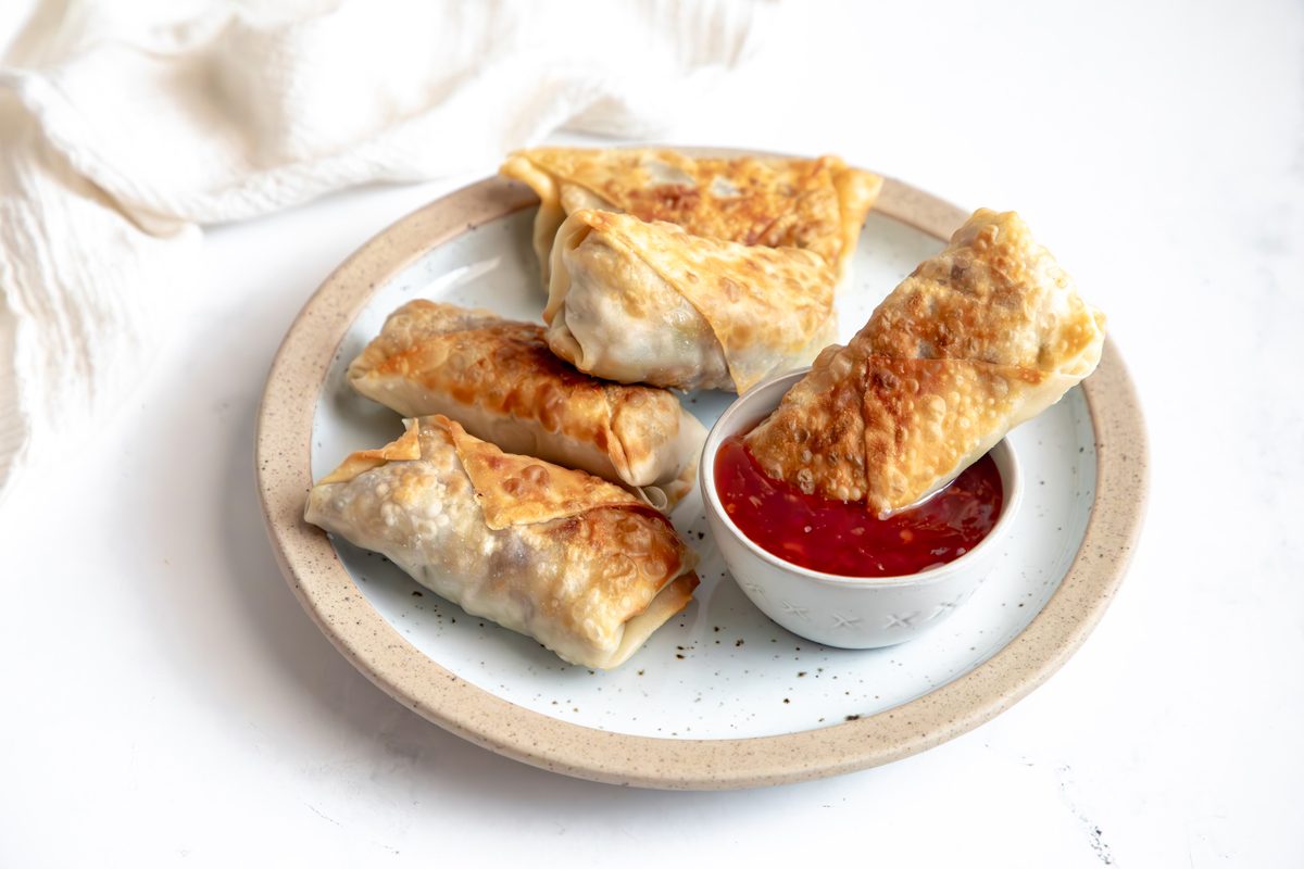 Close up shot for Taste of Home Sausage Egg Rolls, egg rolls on a plate with sweet chili sauce.