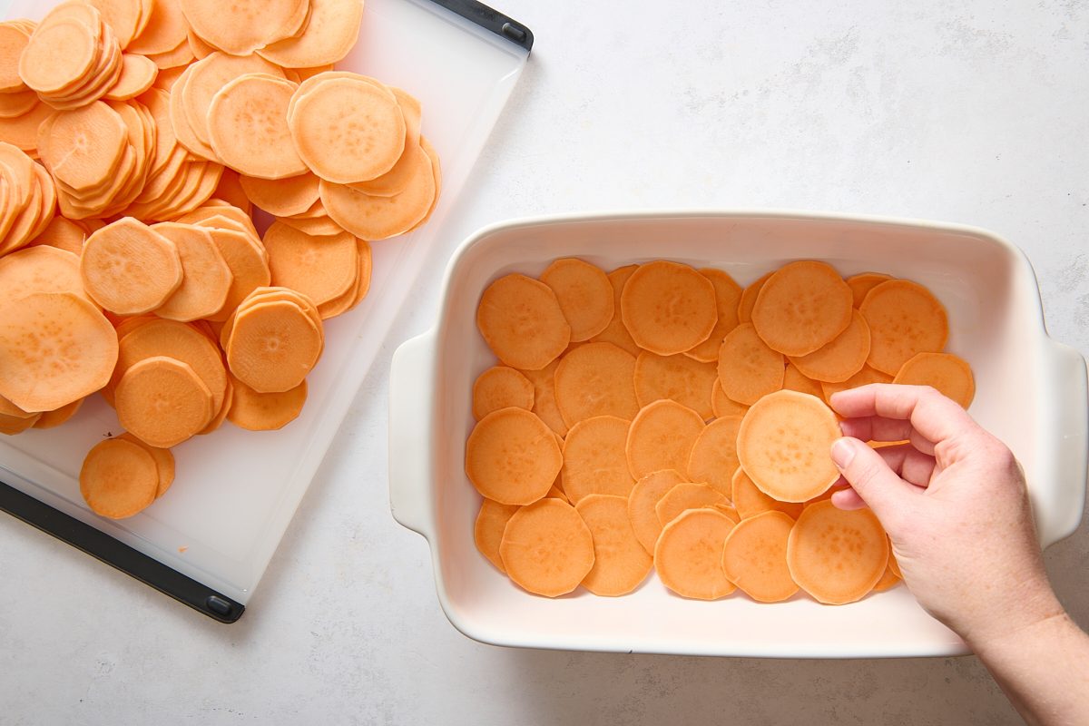 Arranging the sliced sweet potatoes in a baking dish