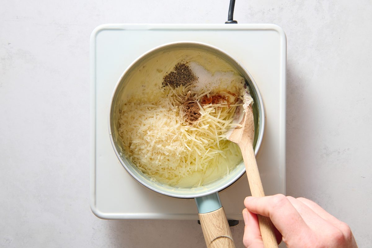 Adding the ingredients to make a cheese sauce to the saucepan