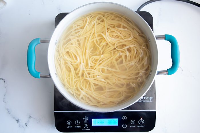 Overhead shot for Taste of Home Seafood Linguine, noodles cooking in a large pot over induction cooktop.