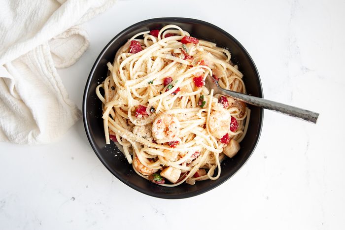 Close up beauty shot for Taste of Home Seafood Linguine being served in a black bowl topped with parmesan cheese.