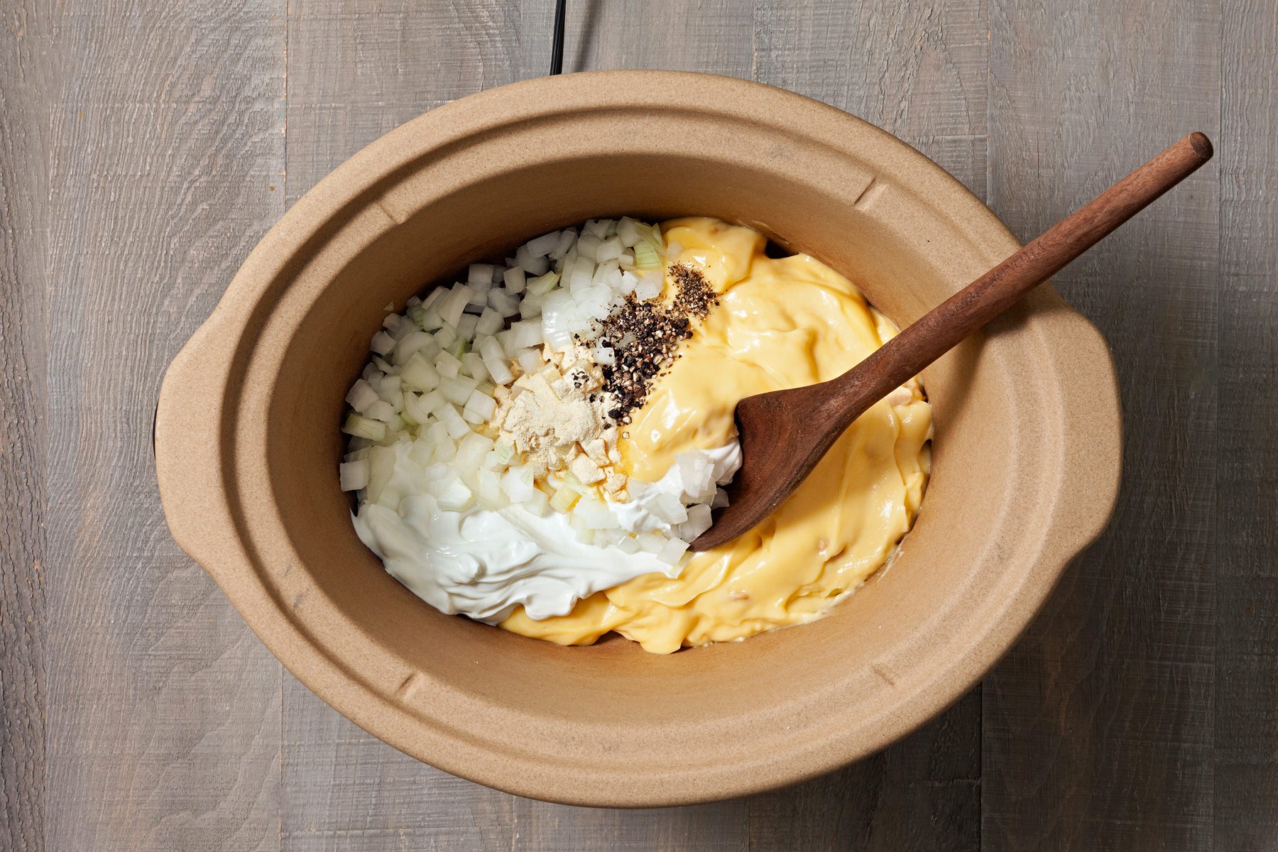 Soup, sour cream, onion, garlic powder, and pepper are combined in a cooker.