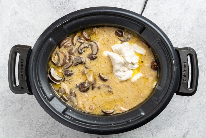 adding the mushrooms and sour cream to the crockpot.