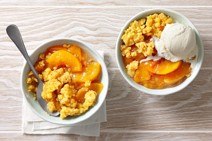 Slow cooker peach cobbler served with vanilla ice cream
