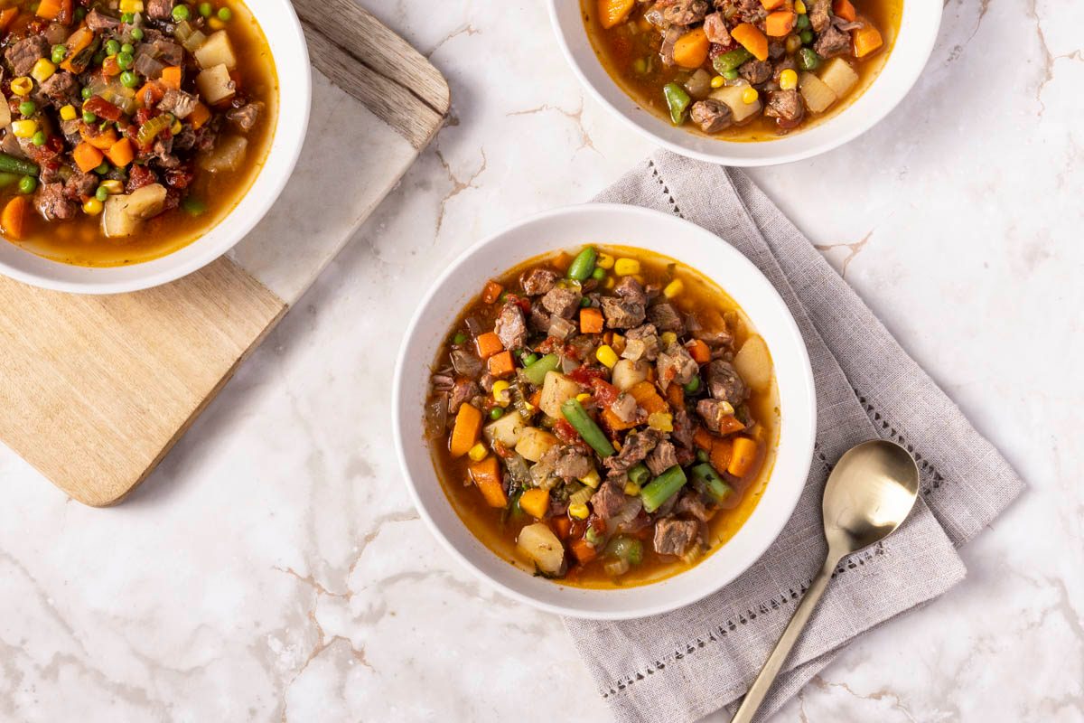 Served Slow Cooker Vegetable Soup in white bowl on white marble table