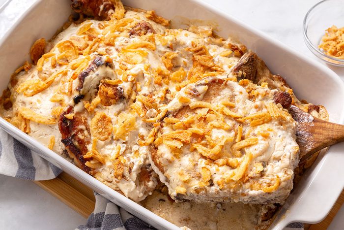 Serving of Smothered Pork Chops being dished out of a baking dish for Taste of Home