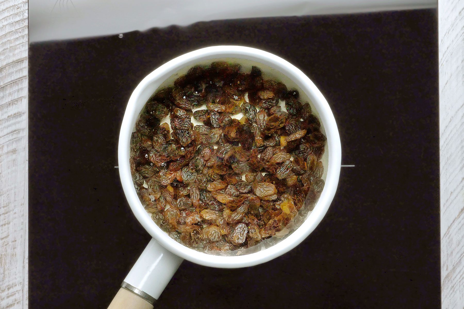 Raisins boiling in water in a small saucepan.