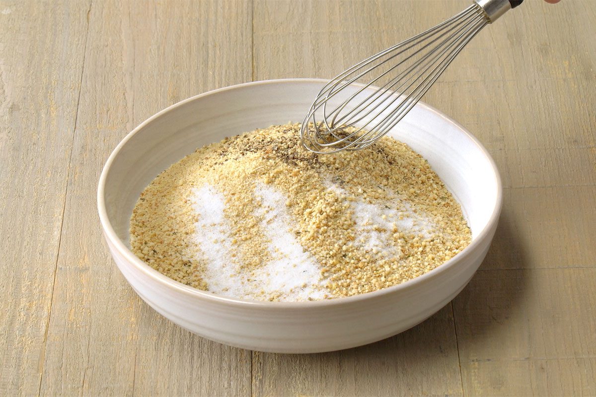 breadcrumbs, salt, and pepper mixed in a separate bowl on a wooden surface