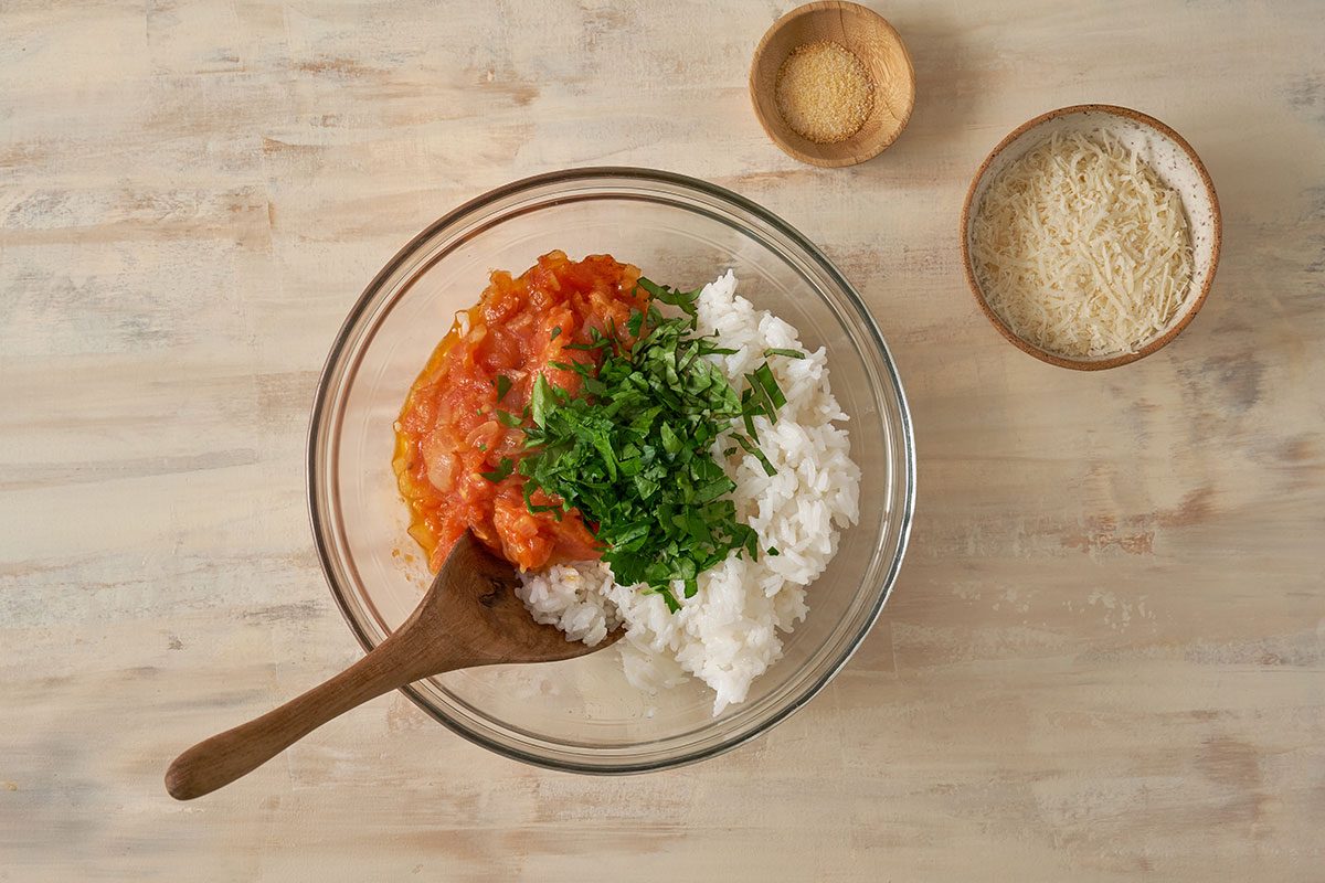 Rice, cheese, parsley, basil, and garlic salt being mixed into the filling for the Stuffed Tomatoes with Rice recipe, by Taste of Home