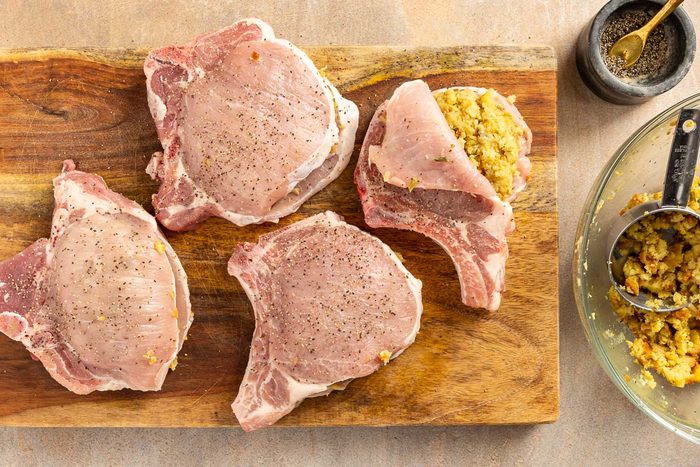 raw pork chops with stuffing on a cutting board
