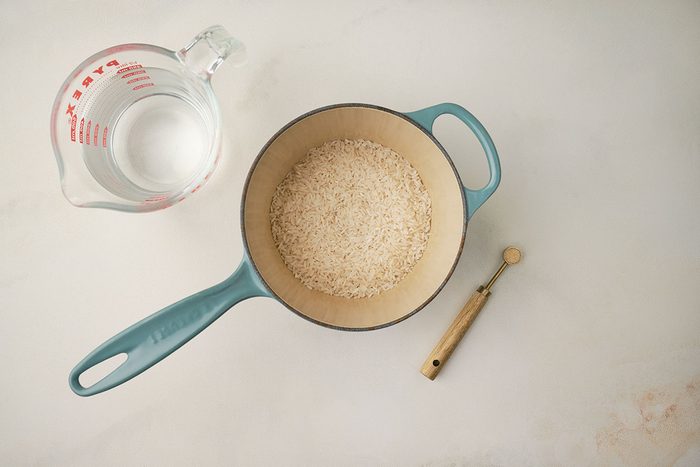Step-by-step image showing rice being cooked in a saucepan with garlic salt and water for Sweet Potato Bowl