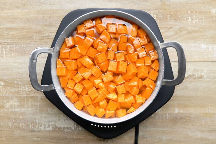 Pieces of sweet potato boiling in a large saucepan