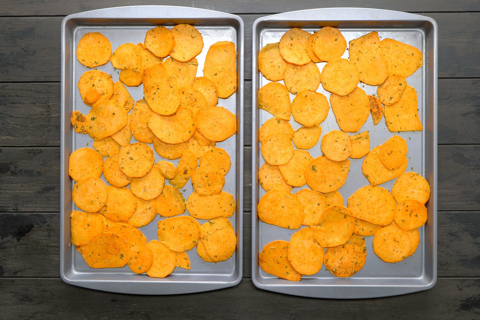 Sliced potatoes placed on baking sheets and seasoned with spices