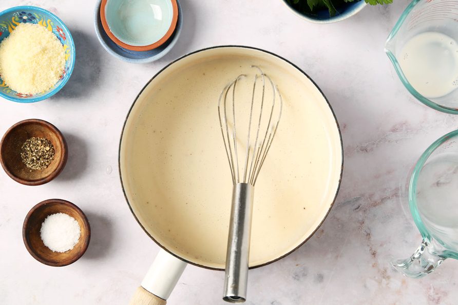 Process of making Taste of Home's Creamed Pearl Onions in a green casserole dish on a grey marble surface.