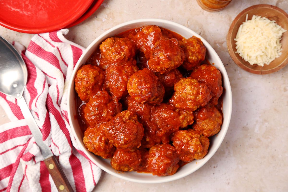Close up of Taste of Home's Instant Pot Meatballs served in a white serving bowl on a brown marble surface.