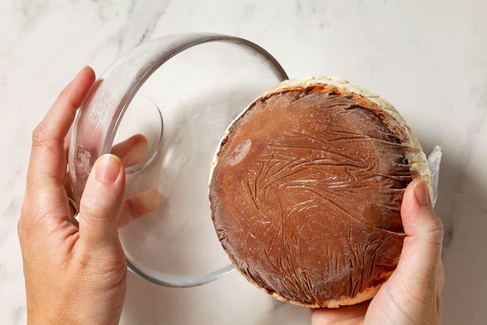 Removing frozen chocolate ice cream from storage wrapped bowl