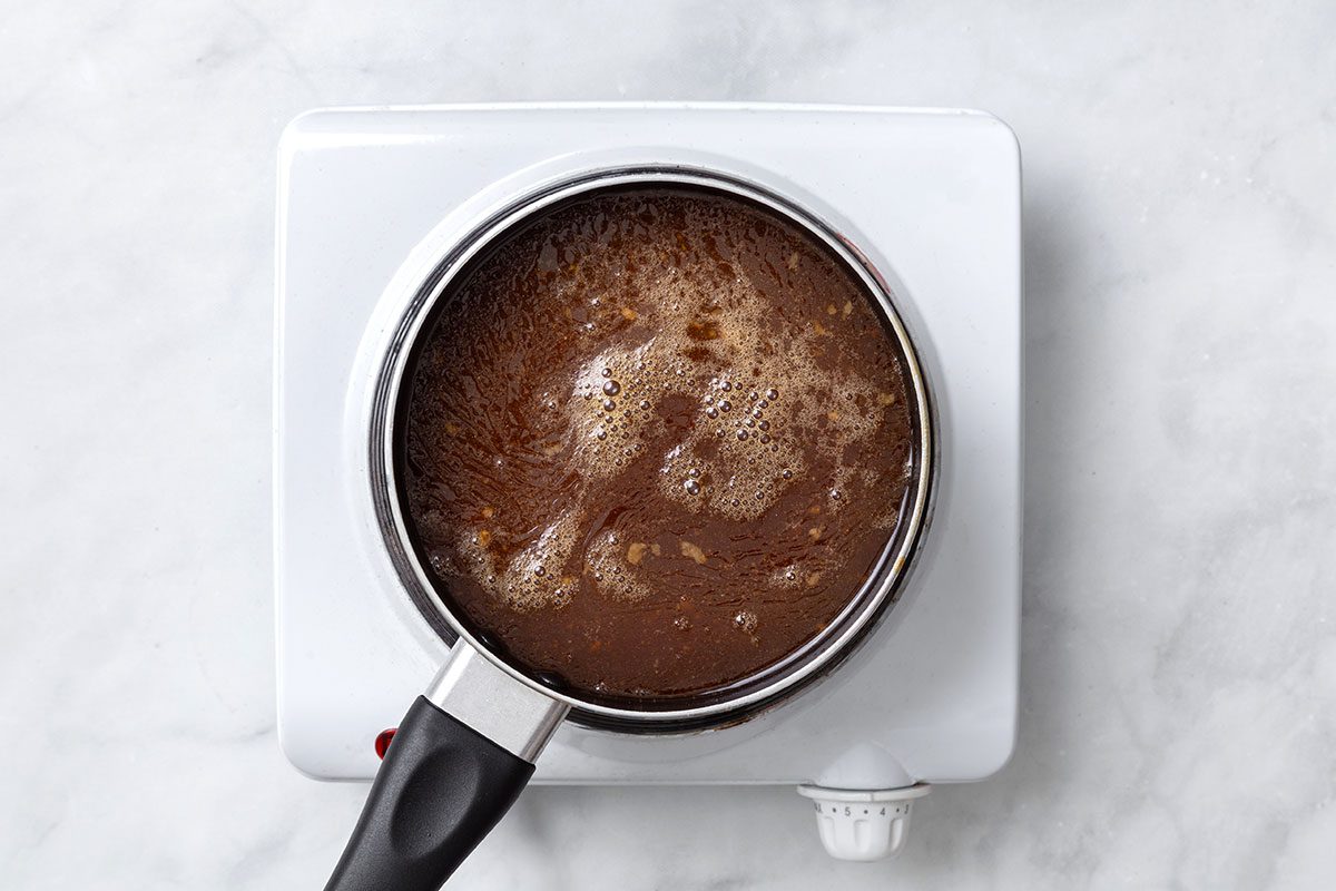 Sauce and chicken juices boiling in a saucepan for step three of Teriyaki Chicken Thighs recipe for Taste of Home